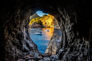 Sailboats viewed through a coastal cave in Mallorca