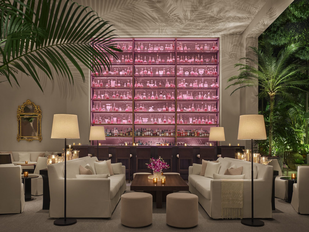 The bar and lounge at Singapore EDITION, featuring a pink glass display and tropical greenery