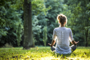 Woman meditating and practicing yoga in a forest by herself.
